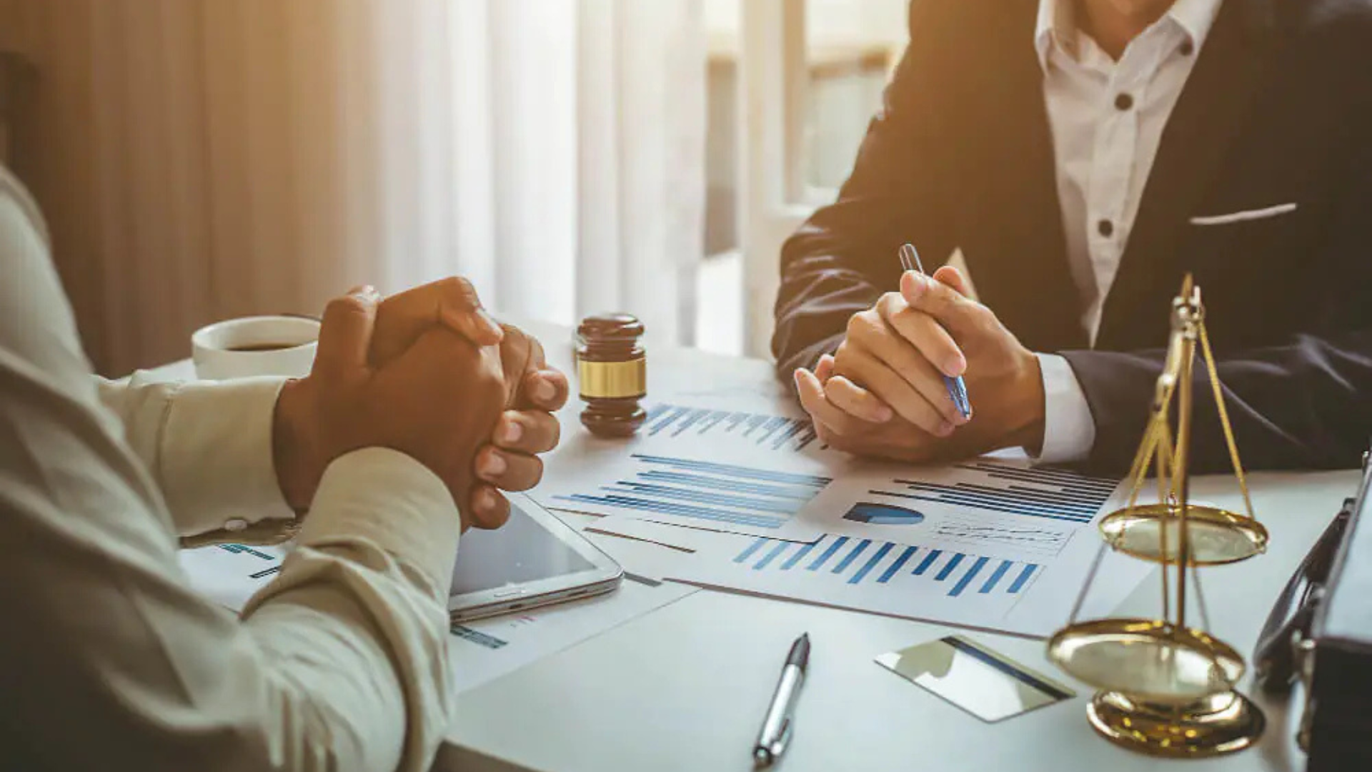 A imagem de uma reunião de negócios com balança da justiça e gráficos ilustra o serviço de recuperação judicial para Pessoa Jurídica.