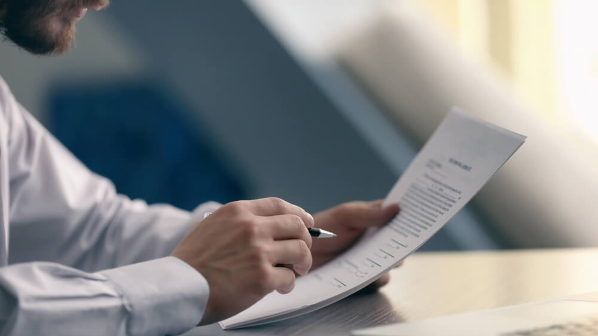 A imagem de uma pessoa assinando documentos ilustra o serviço de revisional de contratos para Pessoa Jurídica, focando em direito bancário.